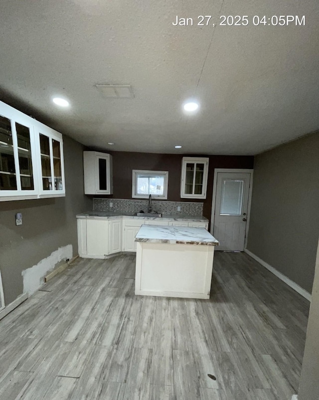 2212 Rugeley St, Bay City, TX 77414 - kitchen with white cabinets, glass insert cabinets, light wood-style flooring, a textured ceiling, and recessed lighting