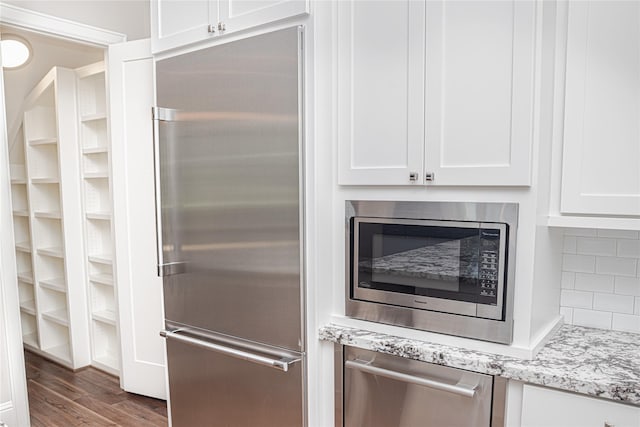 1530 Cunningham Parc Ln, Houston, TX 77055 - kitchen with built in appliances, white cabinets, dark wood finished floors, light stone countertops, and decorative backsplash