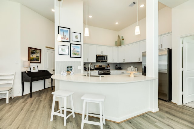 541 Green Meadows Dr, West Columbia, TX 77486 - kitchen featuring stainless steel appliances, a high ceiling, light wood-type flooring, a breakfast bar, and white cabinetry