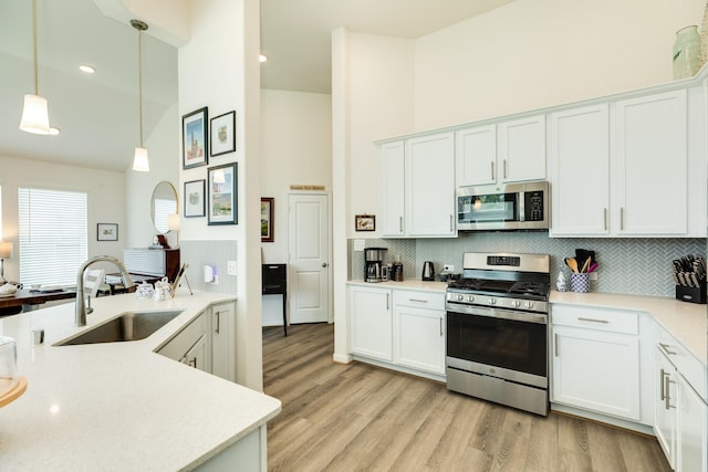 541 Green Meadows Dr, West Columbia, TX 77486 - kitchen with appliances with stainless steel finishes, a high ceiling, backsplash, pendant lighting, and light wood-type flooring