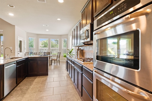 10002 Mahaffey Rd, Tomball, TX 77375 - kitchen with stainless steel appliances, decorative backsplash, recessed lighting, light stone counters, and dark brown cabinets
