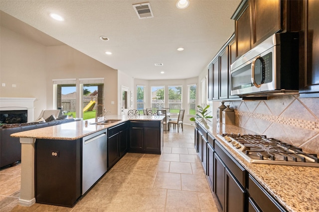 10002 Mahaffey Rd, Tomball, TX 77375 - kitchen with appliances with stainless steel finishes, decorative backsplash, recessed lighting, light stone counters, and a glass covered fireplace