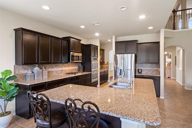 10002 Mahaffey Rd, Tomball, TX 77375 - kitchen with arched walkways, stainless steel appliances, dark brown cabinets, a breakfast bar area, and recessed lighting