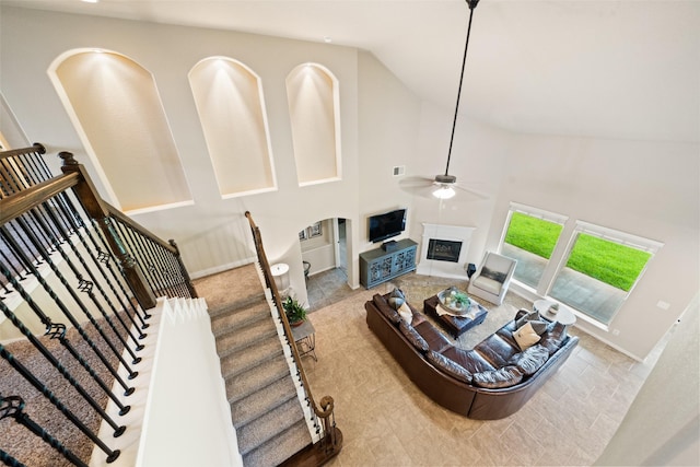 10002 Mahaffey Rd, Tomball, TX 77375 - living room with a ceiling fan, a glass covered fireplace, high vaulted ceiling, and arched walkways