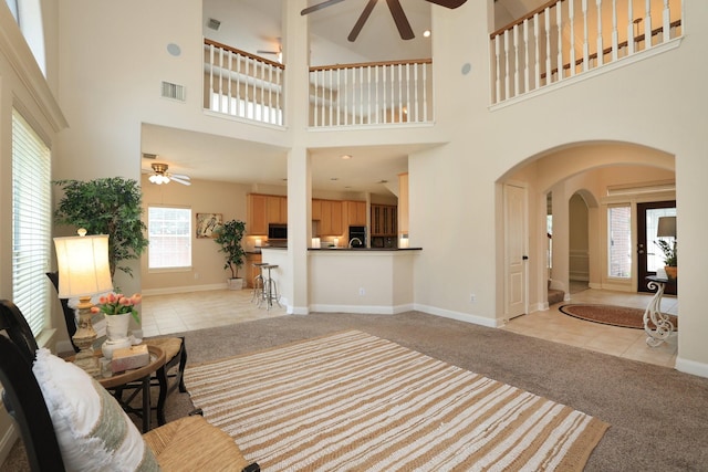 17430 Autumn Oak Way, Spring, TX 77379 - living room with a ceiling fan, light carpet, arched walkways, light tile patterned flooring, and a high ceiling