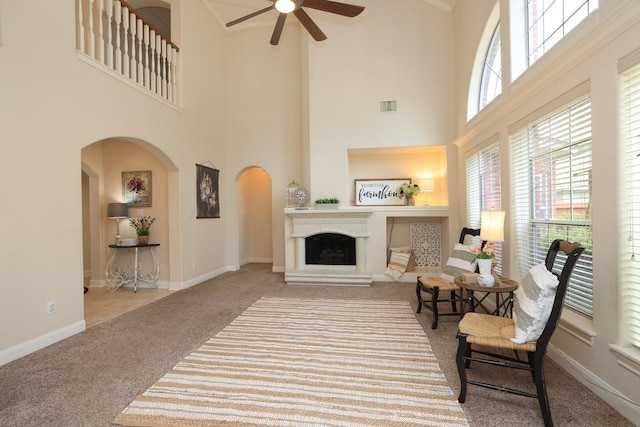 17430 Autumn Oak Way, Spring, TX 77379 - carpeted living room featuring arched walkways, a ceiling fan, a towering ceiling, and a fireplace with raised hearth