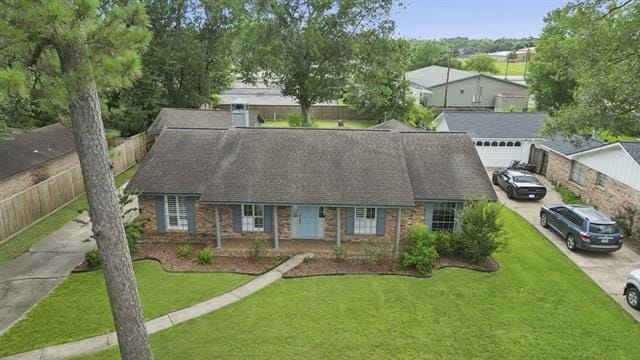 1135 Ivy Ln, Beaumont, TX 77706 - view of front facade with driveway, brick siding, a front lawn, and roof with shingles
