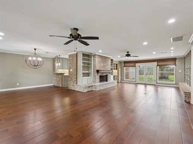 1135 Ivy Ln, Beaumont, TX 77706 - unfurnished living room featuring ceiling fan, a brick fireplace, dark wood-style flooring, recessed lighting, and a chandelier