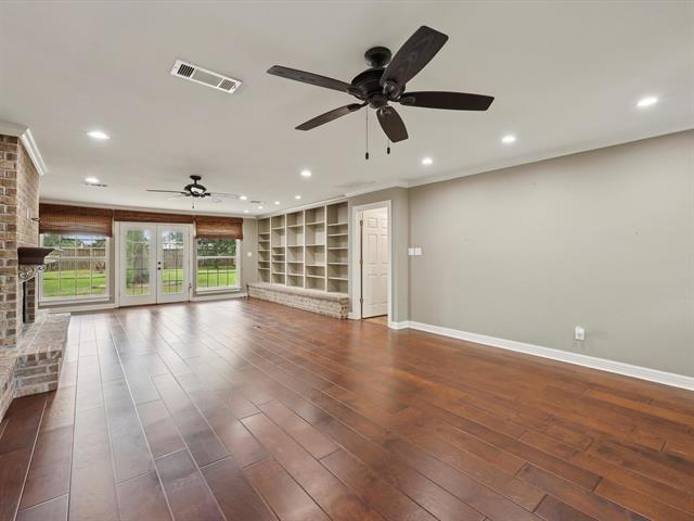 1135 Ivy Ln, Beaumont, TX 77706 - unfurnished living room featuring a ceiling fan, a brick fireplace, wood finished floors, recessed lighting, and ornamental molding