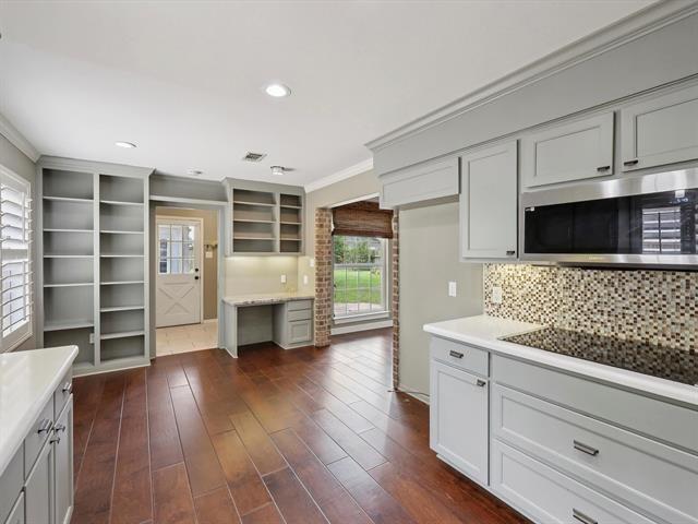 1135 Ivy Ln, Beaumont, TX 77706 - kitchen with stainless steel microwave, plenty of natural light, ornamental molding, light countertops, and decorative backsplash