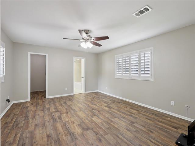1135 Ivy Ln, Beaumont, TX 77706 - unfurnished bedroom with a spacious closet, wood finished floors, a ceiling fan, a closet, and connected bathroom