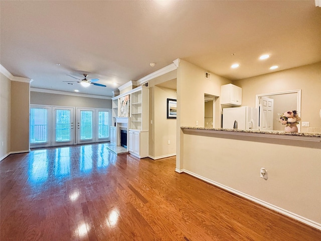 2400 Mccue Rd Unit 345, Houston, TX 77056 - unfurnished living room featuring a ceiling fan, wood finished floors, a fireplace with raised hearth, ornamental molding, and recessed lighting