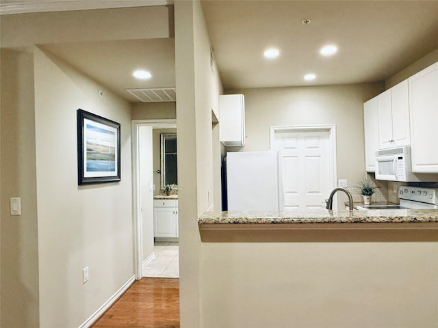 2400 Mccue Rd Unit 345, Houston, TX 77056 - kitchen featuring white appliances, recessed lighting, white cabinets, light stone countertops, and a peninsula