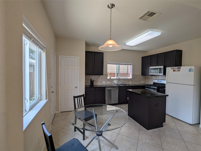 7206 Sunburst Meadow Dr, Houston, TX 77083 - kitchen featuring stainless steel appliances, dark countertops, decorative backsplash, dark cabinetry, and a kitchen island