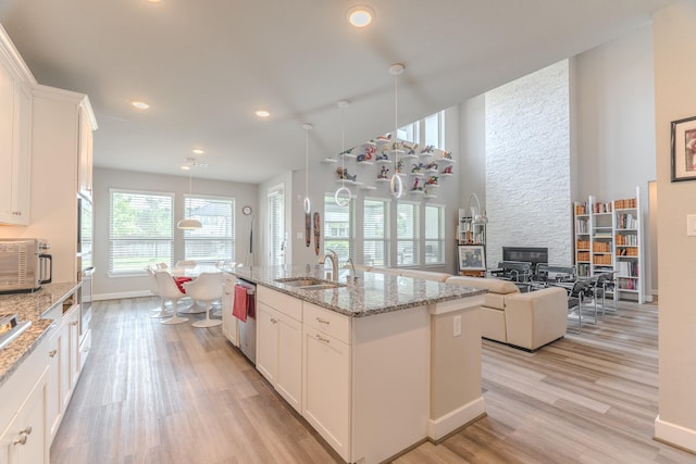 40 Snowdrop Lily Dr, Tomball, TX 77375 - kitchen with light wood-style flooring, stainless steel appliances, white cabinets, recessed lighting, and a center island with sink