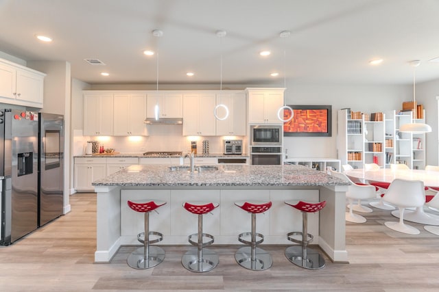 40 Snowdrop Lily Dr, Tomball, TX 77375 - kitchen featuring stainless steel appliances, light wood-style flooring, a kitchen bar, white cabinetry, and recessed lighting