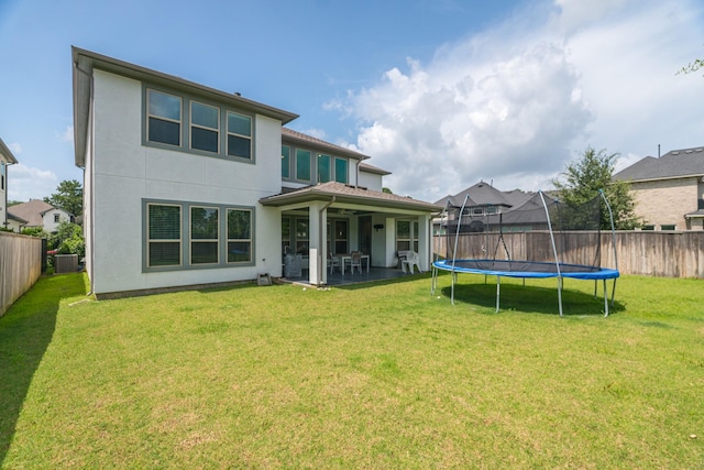 40 Snowdrop Lily Dr, Tomball, TX 77375 - back of house with a trampoline, a fenced backyard, a patio area, and stucco siding