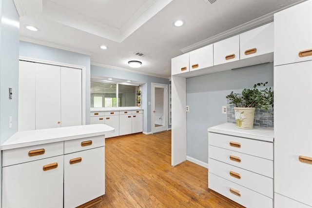 9310 Carvel Ln, Houston, TX 77036 - kitchen featuring crown molding, light countertops, recessed lighting, light wood-style floors, and white cabinets