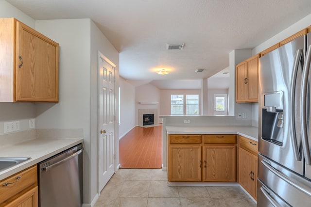 17203 Morning Blossom Pl, Houston, TX 77084 - kitchen featuring appliances with stainless steel finishes, open floor plan, a peninsula, light countertops, and light tile patterned floors