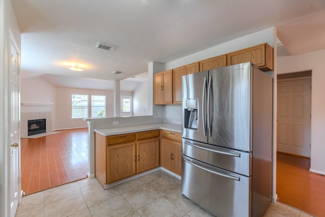 17203 Morning Blossom Pl, Houston, TX 77084 - kitchen featuring stainless steel fridge with ice dispenser, a peninsula, light countertops, open floor plan, and light tile patterned flooring