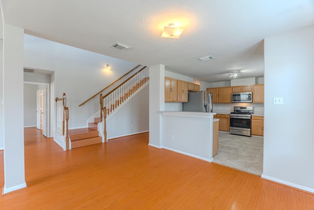 17203 Morning Blossom Pl, Houston, TX 77084 - kitchen featuring stainless steel appliances, light wood-style floors, light countertops, open floor plan, and a peninsula