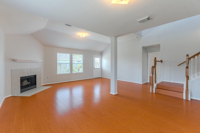 17203 Morning Blossom Pl, Houston, TX 77084 - unfurnished living room with wood finished floors, a tile fireplace, stairs, and vaulted ceiling