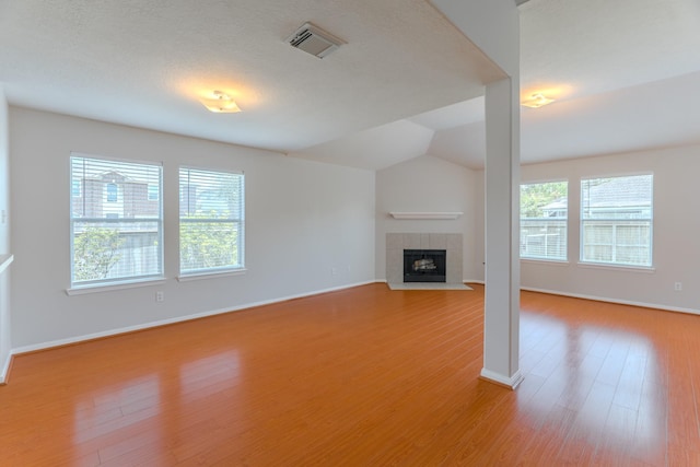 17203 Morning Blossom Pl, Houston, TX 77084 - unfurnished living room featuring plenty of natural light, light wood-style floors, a fireplace, and vaulted ceiling