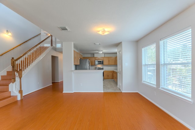 17203 Morning Blossom Pl, Houston, TX 77084 - kitchen featuring stainless steel appliances, light wood-type flooring, light countertops, open floor plan, and a peninsula