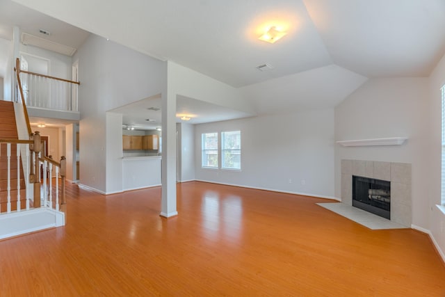 17203 Morning Blossom Pl, Houston, TX 77084 - unfurnished living room with wood finished floors, a fireplace, stairs, and lofted ceiling