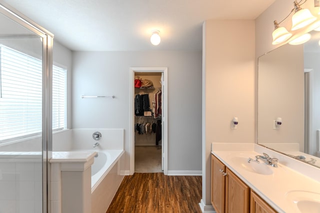 17203 Morning Blossom Pl, Houston, TX 77084 - bathroom with double vanity, a garden tub, wood finished floors, a spacious closet, and a shower with shower door