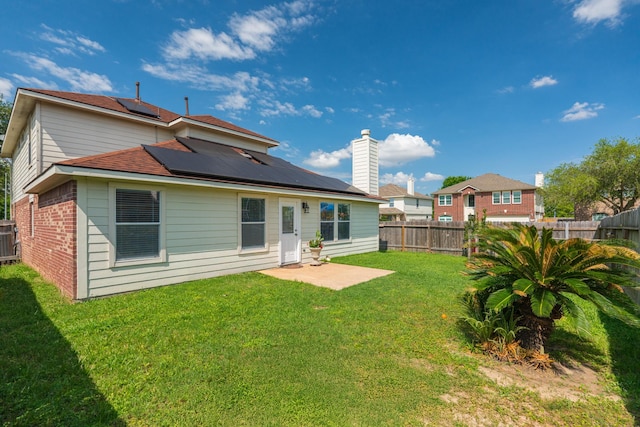 17203 Morning Blossom Pl, Houston, TX 77084 - back of house with roof mounted solar panels, a fenced backyard, a patio, brick siding, and a chimney