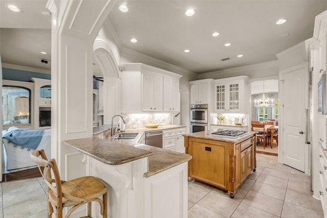 130 Amulet Oaks Ct, The Woodlands, TX 77382 - kitchen with stainless steel appliances, ornamental molding, backsplash, light stone counters, and arched walkways