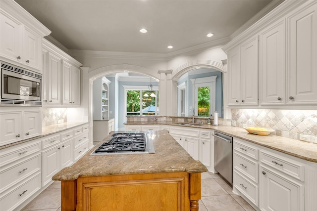 130 Amulet Oaks Ct, The Woodlands, TX 77382 - kitchen with stainless steel appliances, arched walkways, a kitchen island, white cabinetry, and light tile patterned flooring