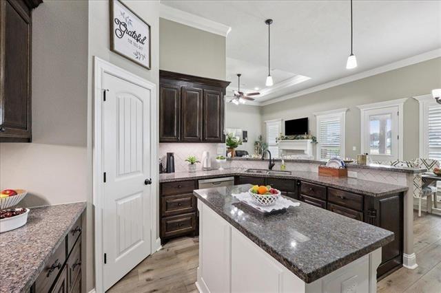 271 Hannah Ln, Lumberton, TX 77657 - kitchen with light wood-style floors, ceiling fan, crown molding, a kitchen island, and dark brown cabinetry