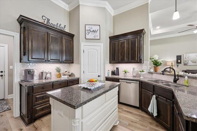 271 Hannah Ln, Lumberton, TX 77657 - kitchen with dishwasher, dark stone countertops, ornamental molding, dark brown cabinetry, and light wood finished floors
