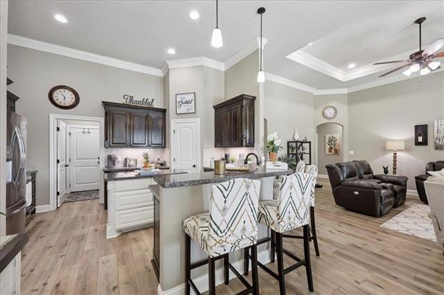 271 Hannah Ln, Lumberton, TX 77657 - kitchen with a kitchen bar, dark brown cabinetry, light wood-style flooring, a ceiling fan, and ornamental molding