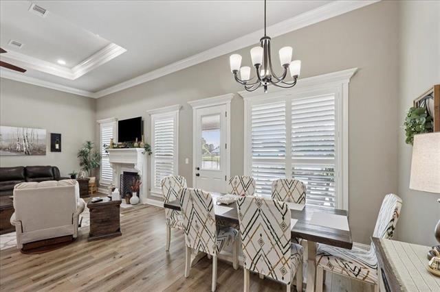 271 Hannah Ln, Lumberton, TX 77657 - dining space with light wood-style flooring, a chandelier, ornamental molding, a tray ceiling, and a fireplace