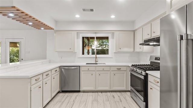 5010 Redstart St, Houston, TX 77035 - kitchen featuring appliances with stainless steel finishes, under cabinet range hood, a peninsula, light countertops, and recessed lighting