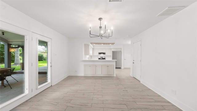 5010 Redstart St, Houston, TX 77035 - kitchen featuring freestanding refrigerator, a chandelier, a peninsula, white cabinets, and light countertops