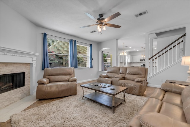 5506 Poundstone Ct, Sugar Land, TX 77479 - living room featuring a ceiling fan, a stone fireplace, stairs, arched walkways, and a chandelier