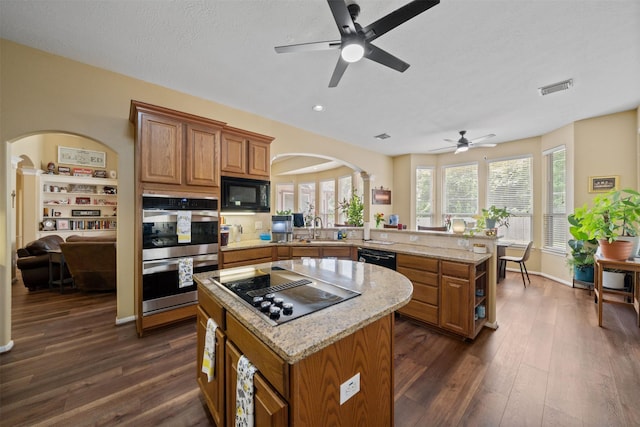 210 Southwood Cir, Baytown, TX 77520 - kitchen with black appliances, arched walkways, brown cabinetry, a peninsula, and recessed lighting