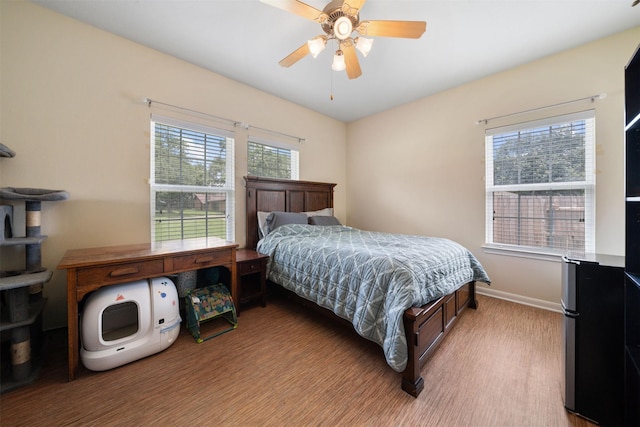 210 Southwood Cir, Baytown, TX 77520 - bedroom featuring light wood-style flooring, freestanding refrigerator, and ceiling fan