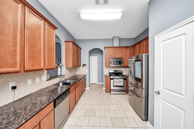 118 Long Canyon Ln, Richmond, TX 77469 - kitchen with stainless steel appliances, decorative backsplash, arched walkways, and dark stone counters