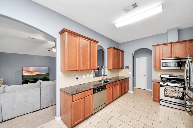 118 Long Canyon Ln, Richmond, TX 77469 - kitchen featuring appliances with stainless steel finishes, arched walkways, open floor plan, ceiling fan, and tasteful backsplash