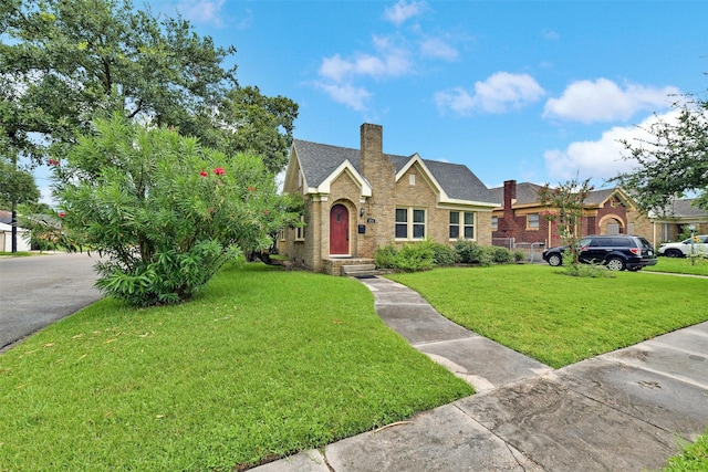 4701 Avenue N 1/2 Ave N 1/2, Galveston, TX 77551 - tudor-style house featuring a front lawn, brick siding, a chimney, and roof with shingles