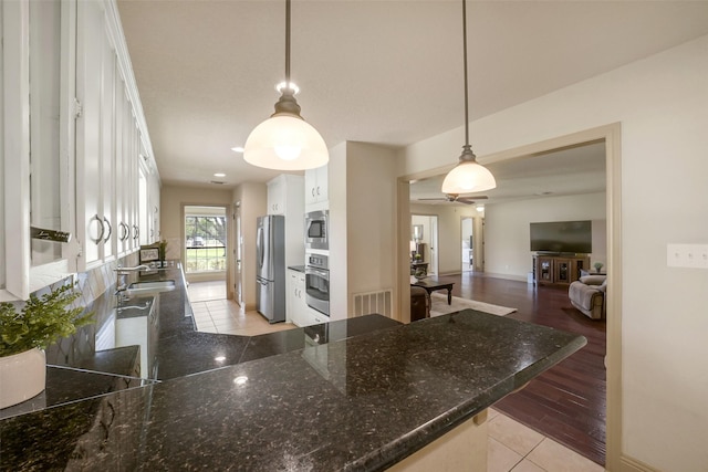 18120 County Road 127, Pearland, TX 77581 - kitchen with stainless steel appliances, white cabinetry, dark stone countertops, and ceiling fan