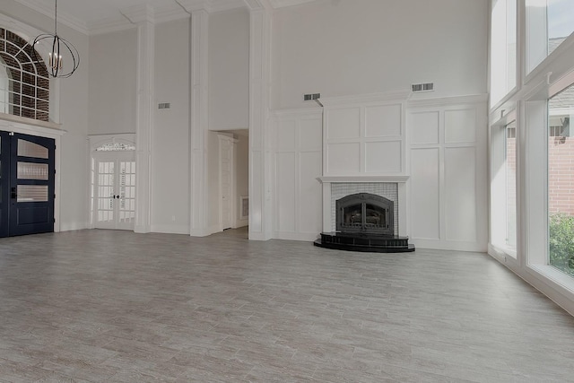 25 Red Sable Pt, The Woodlands, TX 77380 - unfurnished living room with a high ceiling, a chandelier, french doors, a fireplace, and crown molding