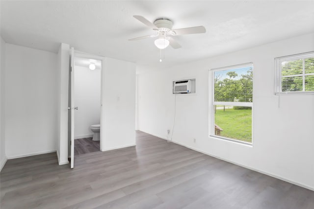 901 6th St, San Leon, TX 77539 - unfurnished bedroom with wood finished floors, a wall mounted air conditioner, and ceiling fan