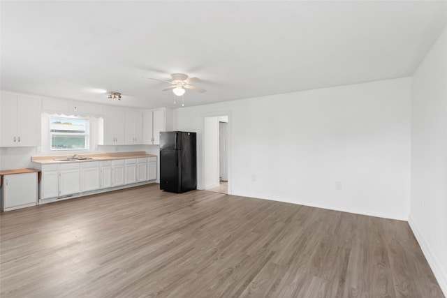 901 6th St, San Leon, TX 77539 - kitchen with freestanding refrigerator, a ceiling fan, light wood-type flooring, and white cabinetry