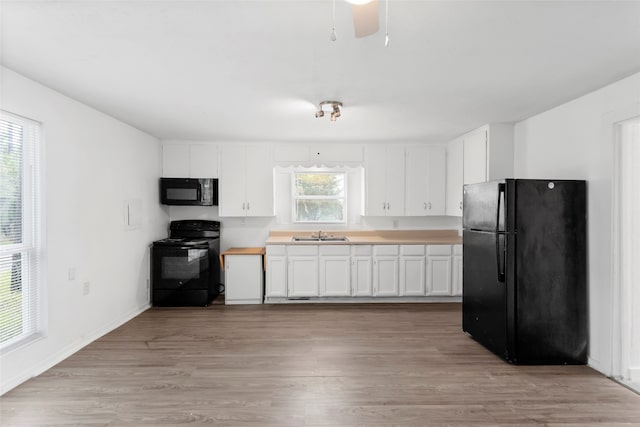 901 6th St, San Leon, TX 77539 - kitchen with black appliances, plenty of natural light, and white cabinetry